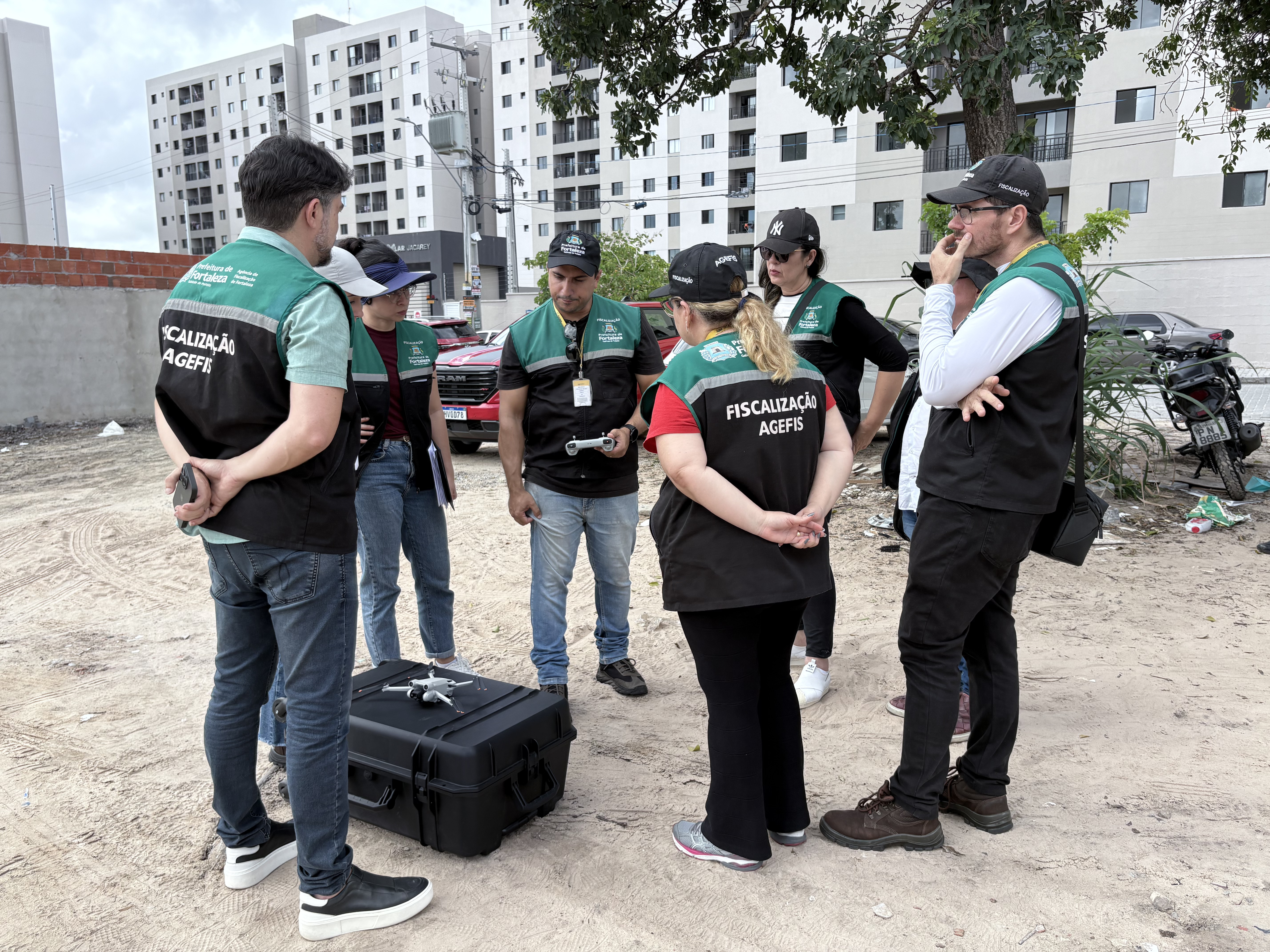 agentes da Agefis em um terreno com um case de drone